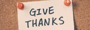 note pinned on cork board with "Give Thanks" written on it